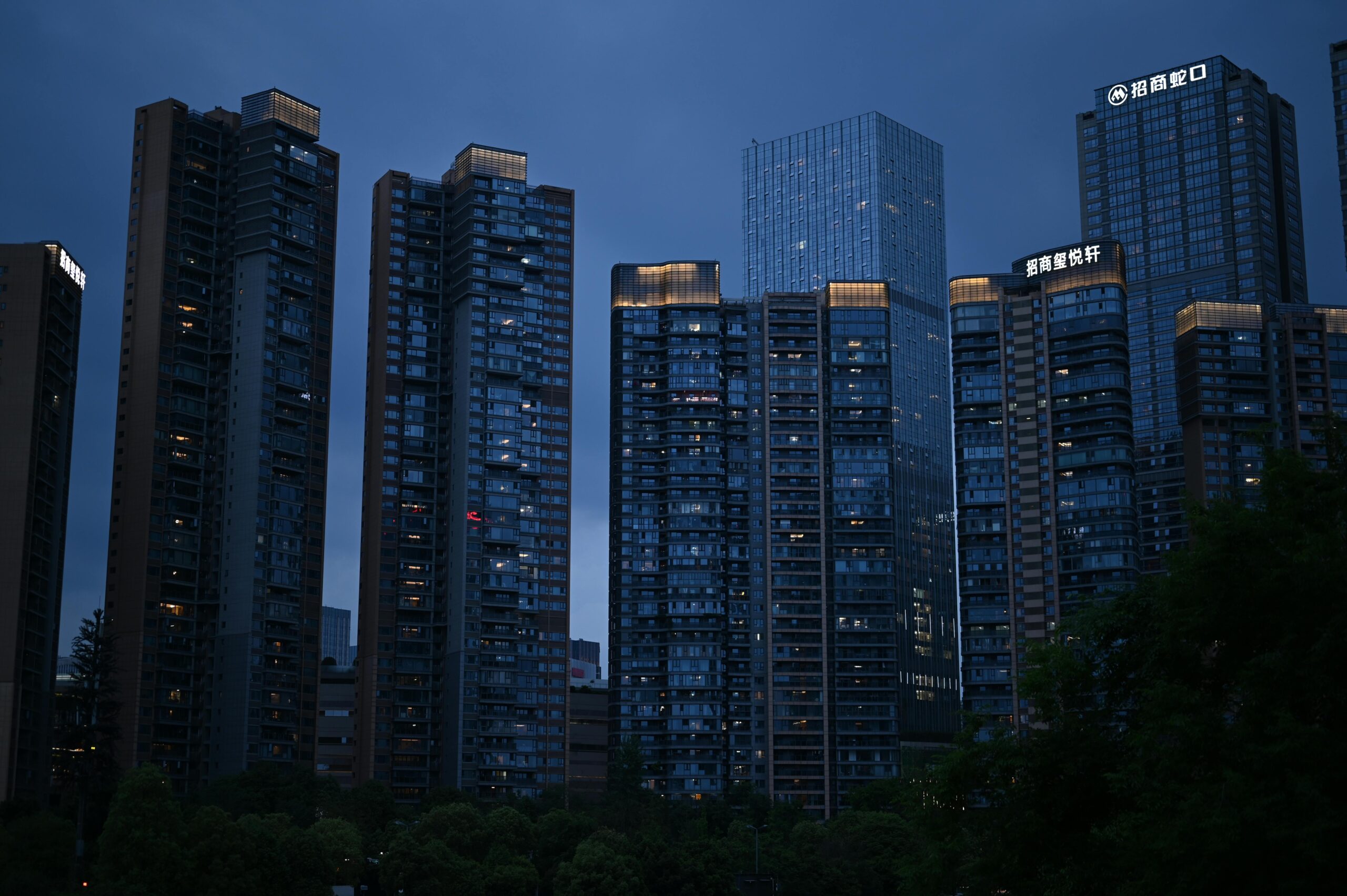 Night view of modern high-rise buildings with illuminated windows in an urban city skyline.